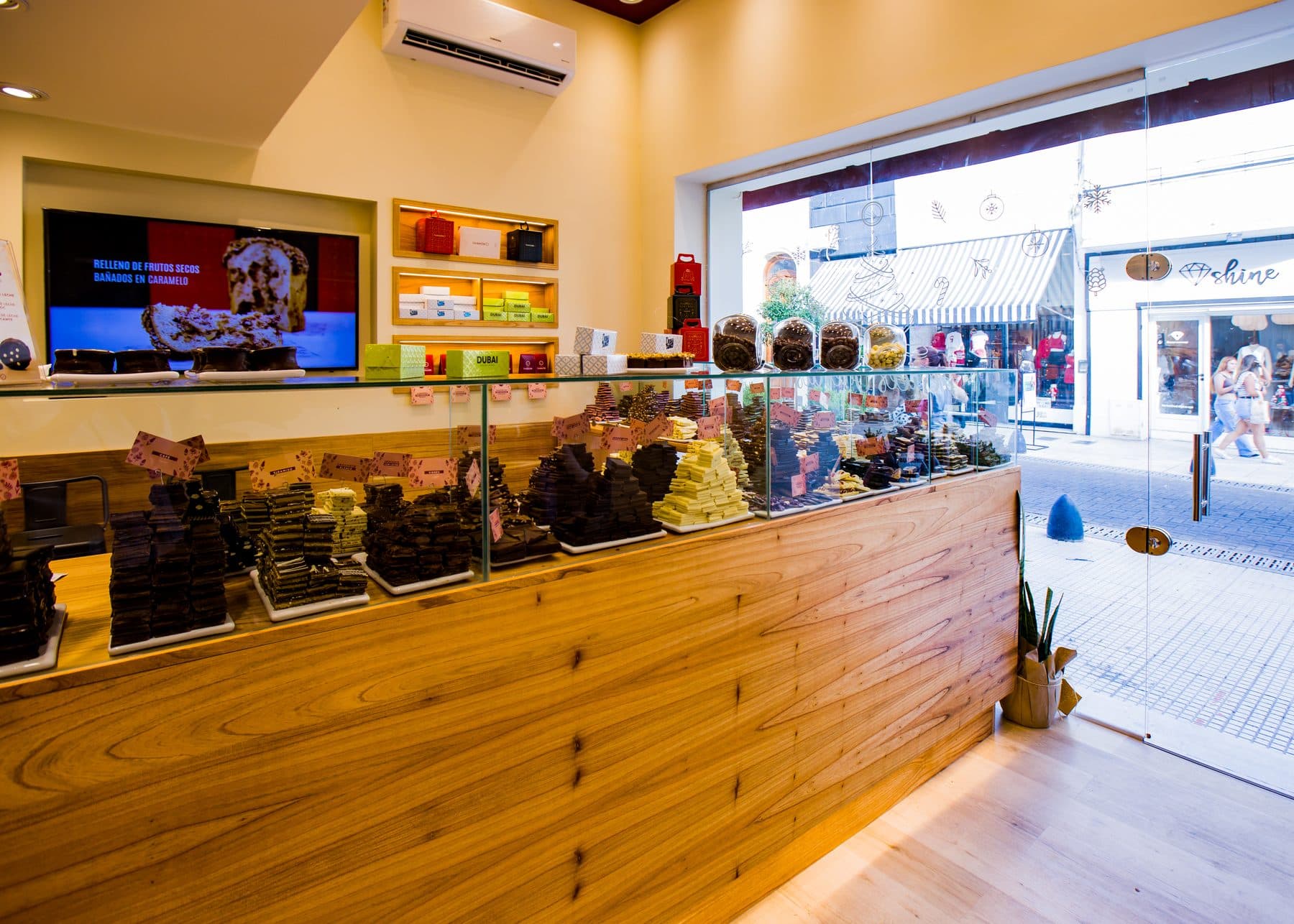 Interior de un local La Pinocha con mostrador de madera y vitrina de chocolates